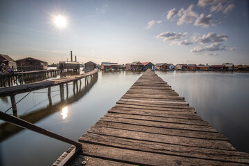 Wooden houses in the water. Holiday resort in the lake at sunset. Long wooden walkways lead to the individual houses. Landscape photo of the floating village of Bokodi, Lake Balaton, Hungary