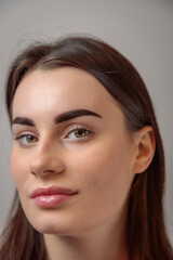 Fototapeta premium Portrait of beautiful young woman showing perfect eyebrows after microblading treatment