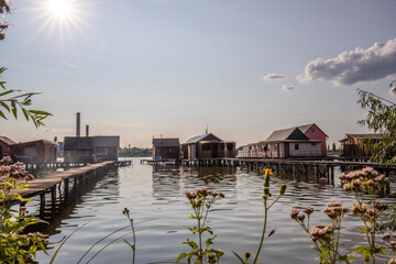 Wooden houses in the water. Holiday resort in the lake at sunset. Long wooden walkways lead to the...