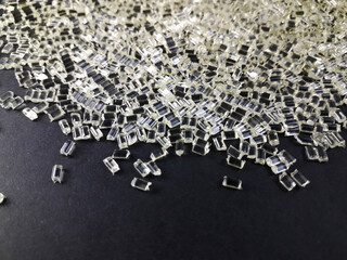 Transparent polycarbonate plastic granules on a black background, one of the main materials in the...