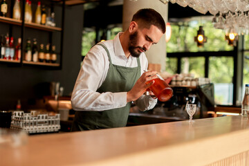 Skilled bartender prepares a cocktail at a stylish bar during a vibrant evening in a bustling city