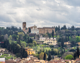 rolling hills dotted with olive trees and tiled rooftops, crowned by what looks like the Abbazia di...