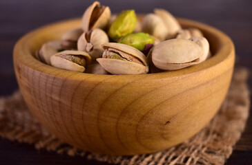 Pistachio nuts in a wooden bowl. Close-up.