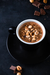 coffee with chocolate and hazelnuts in close-up on a black background