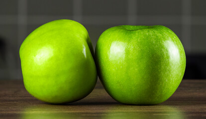 Fresh green apples placed closely on a wooden table against a blurred background