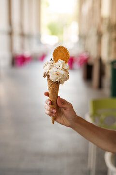 Woman standing in the street holding a waffle Cone with Pistachio and Stracciatella gelato, whipped cream and cookie, Amalfi Coast, Italy
