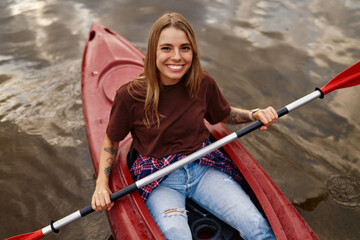 A Smiling Young Woman Kayaking on Calm Waters, Embracing Adventure and Enjoying Natures Beauty