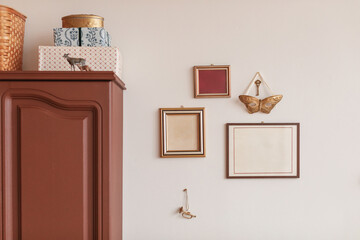 Blank picture frames hanging on a wall next to assorted boxes, containers and baskets on top of a cupboard