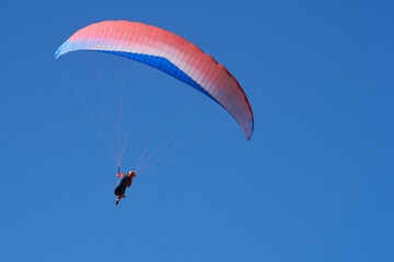 Paraglider under red and blue dome in blue sky. Copy space.