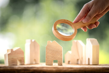 Businessman use the magnifying glass with scan and x-ray with searching the home model in the public park, Loan for real estate or saving money for buy a new house to family in the future concept.
