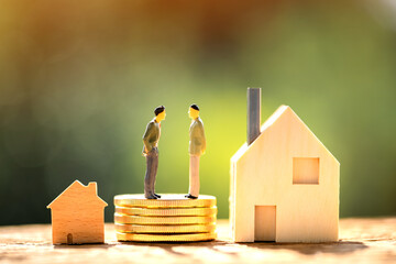 Two businessmen standing on the stack coins are negotiating for buy and sell or exchange purchase a home put on the wood in the public park, Loan and investment for real estate concept.