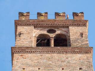 Belfry of an italian medieval church showing brick walls and arches with clear sky in Busseto, Parma, Italy