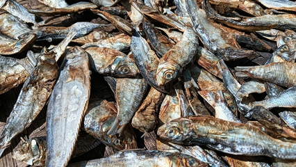 Salted fish being dried on a woven bamboo tray, showcasing texture and traditional details in food processing.