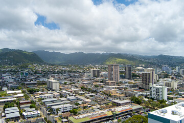 skyscrapers, apartments and office buildings with lush green trees, cars on the street, blue sky and clouds in downtown Honolulu Hawaii USA
