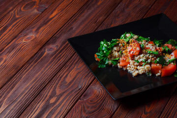 Salad with green leaves and vegetables. Lean vegetarian dish. Light salad organic mix lettuce with tomatoes, bulgur, parsley, seasoned roasted sesame seeds.