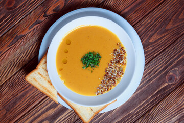 Vegetable soup with bread on wooden tray. White bowl on dark plank background. Top view. Copy space.