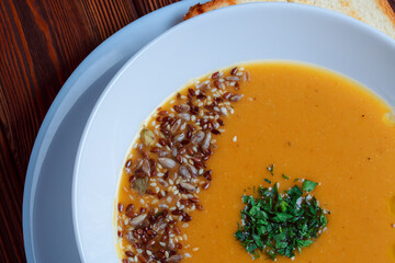 Vegetable soup with bread on wooden tray. White bowl on dark plank background. Top view. Copy space.