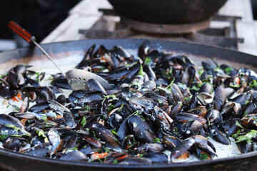 Mussels in a cauldron. Food court. Street food. Mussels cooked in shell. Mussels cooked in sauce, cauldron. Cooking a seafood dish