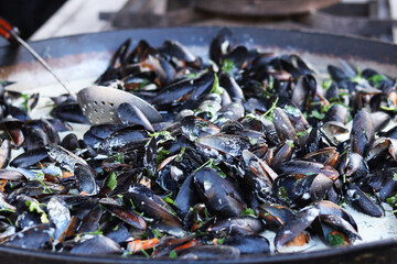 Mussels in a cauldron. Food court. Street food. Mussels cooked in shell. Mussels cooked in sauce, cauldron. Cooking a seafood dish