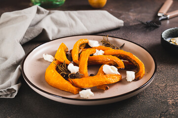 Baked pumpkin with ricotta and rosemary on a plate on the table