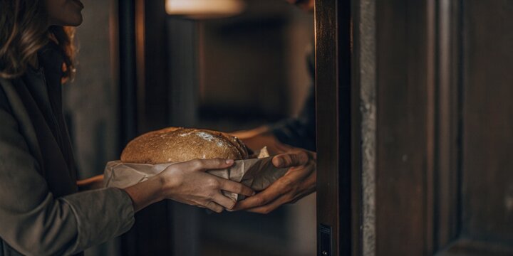 Person Receiving Fresh Loaf of Bread at Doorstep