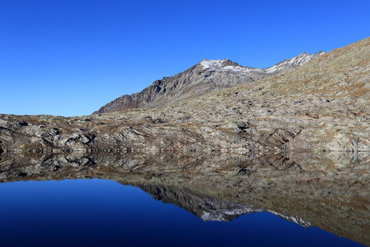 Quiet alpine lake with mountains reflections on the water surface