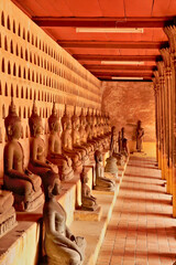 Ceramic buddha statues, sculptures in different sizes lined up in a row in the cloister wall of Wat...