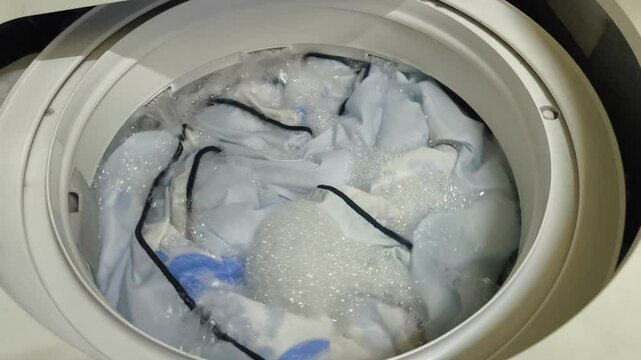 Washing blankets in a top-loading washing machine. Laundry and house keeping concept