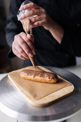 Woman pastry chef decorating chocolate eclair