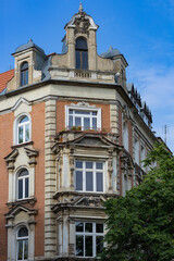 Fototapeta premium Historic European building facade with intricate architectural details, vintage windows and a beautifully preserved corner design under a bright blue sky. Heritage and classic architecture