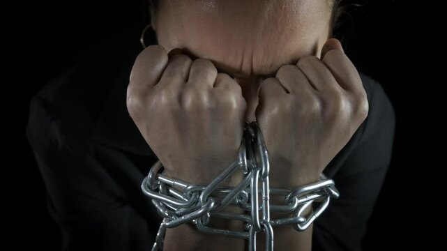 Female in crisis with bound hands. A crying and stressed woman suffer from personal crisis with chained hands. A concept of social and personal issues in life.