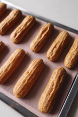 golden brown eclairs on a pink baking sheet