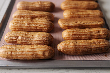 golden brown eclairs on a pink baking sheet
