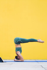 Sporty woman stretching on yoga mat on yellow background