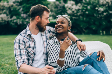 Couple resting on grass and hugging in park