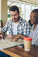 Cheerful couple discussing route on map indoors