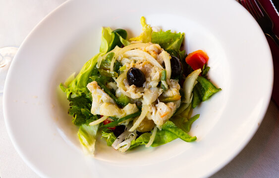 Tasty salad esqueixada of shredded salt cod, onions, greens and olives. Traditional Catalan dish..