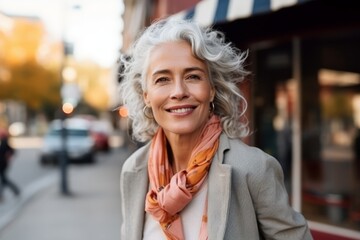 Portrait of happy senior woman walking in city street on autumn day