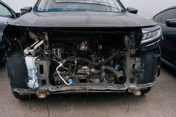 Repair auto after accident, parts replacement in vehicle repair workshop. Close-up of disassembled black car without bumper at service station. Concept of car service, repair and maintenance.