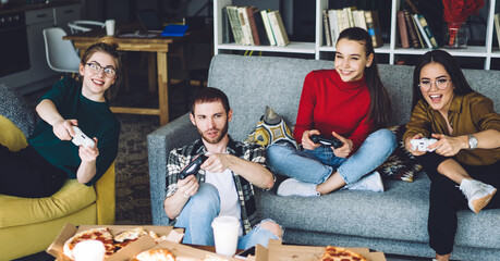 People playing video game with game pad placing in different pose on sofa and armchair © BullRun