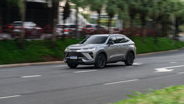 Grey GWM Haval H6 GT in movement, Hyrbid SUV in city street, High Resolution