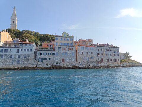 "Panoramic View of a Coastal Town Rovin with a Church Tower Taken from a Boat Under a Clear Blue Sky