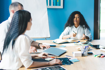 Attentive multiethnic office workers discussing graphs while sitting at table