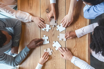 Collaboration concept, top view of creative multiracial team sitting around table and putting...