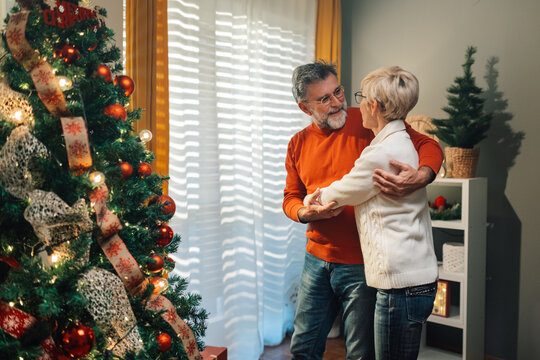 Senior couple dancing in front of christmas tree