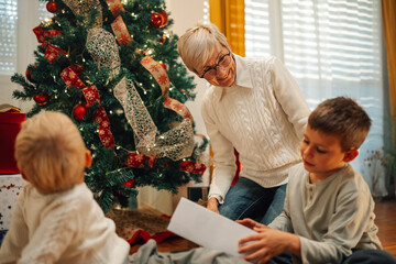 Grandmother helping grandchildren opening christmas presents