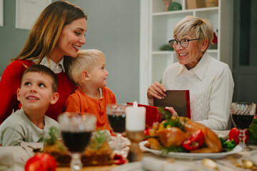Family giving gift to grandmother during christmas dinner