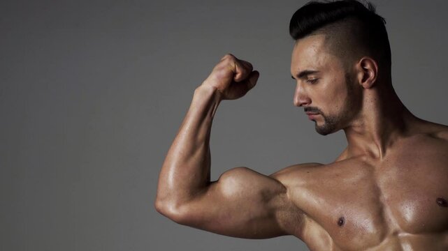 Muscular sexy man man flexing biceps. Male athlete, sportsman flexing bicep, looking at muscle biceps. Male Muscular biceps arm. Hand, man arm biceps Close-up. Strong, sexy and topless male model.