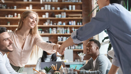 Young asian guy and pretty girl shaking hands during business training, business education concept, office interior