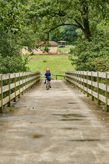 A child crossing a bridge with his bicycle